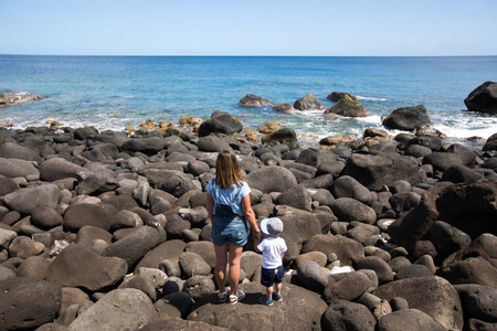 母子俩沿着海边散步。周末在海滩。海滩石。