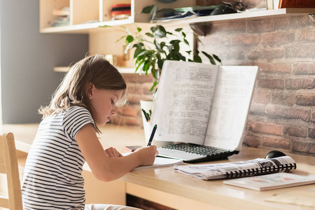 远程在线学习自我隔离的概念。孩子坐在家里用笔记本电脑上课。