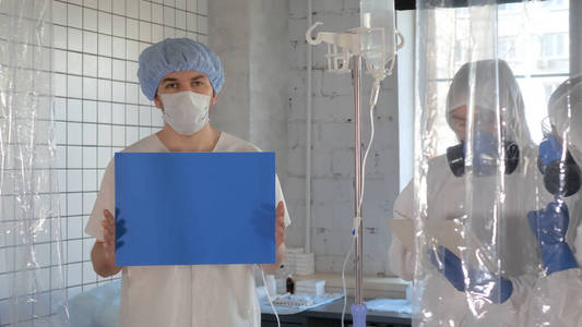 病人拿着白板，穿着防护服的医生在工作。