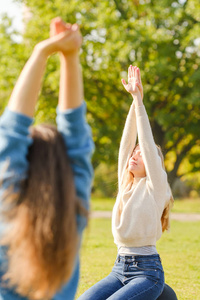 A group of young people meditate outdoors in a park. 