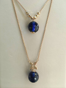  Sapphire pendants on gold chains in a jewelry store window. 