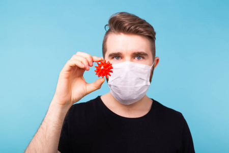 Covid19，疫苗开发和医学概念戴着流感面罩和防护手套的男子持有冠状病毒模型。