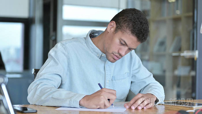 雄心勃勃的非洲男人用笔在纸上写字