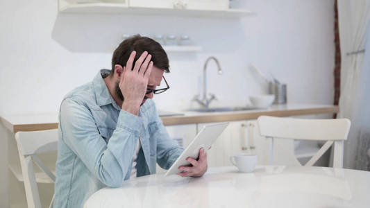 Sad Beard Young Man Facing Loss on Tablet 