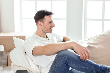 快乐的男人坐在他新公寓的沙发上