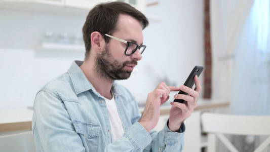 Focused Beard Young Man using Smartphone 