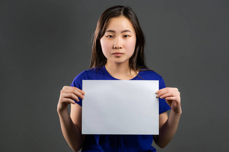 漂亮的亚洲女孩拿着白色的a4纸海报.复制空间.