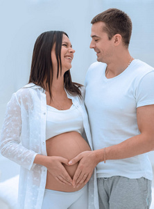 丈夫和怀孕的妻子双手合十放在肚子上，形状像心脏