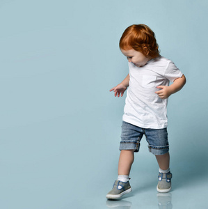 小姜色幼儿男孩或女孩穿着白色t恤,袜子和鞋子,牛仔短裤.