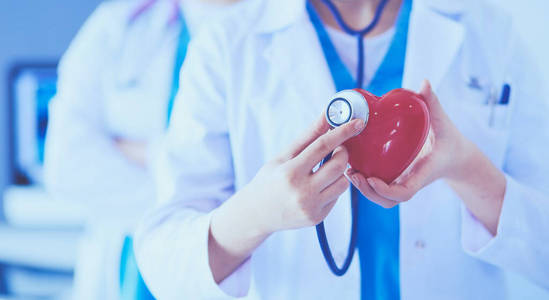 两名年轻医生用听诊器夹着心脏切下的照片。