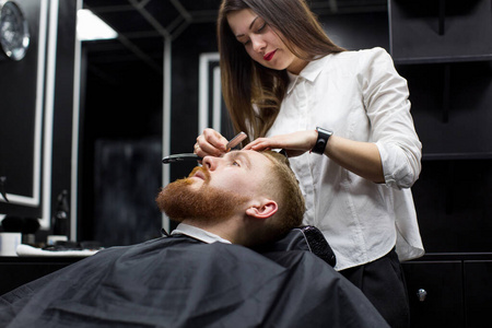 发型师女孩在理发店刮胡子.照片