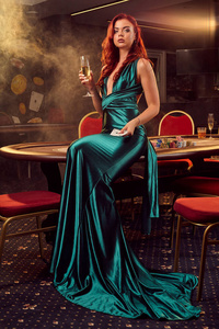 在豪华赌场里，年轻漂亮的女人正对着牌桌摆姿势。