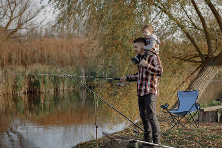 父亲带着小儿子早上在河边钓鱼