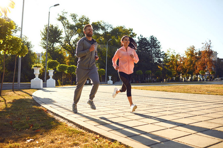 一对运动型夫妇早晨沿着城市街道跑步。