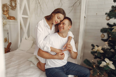 Elegant couple sitting on a bed near christmas tree