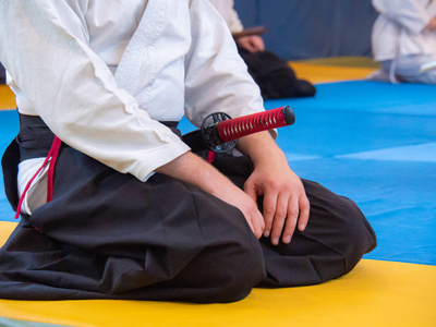 武术指导员与武士刀在研讨会上坐在坐姿.正面视图照片