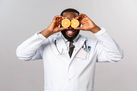 快乐搞笑身穿白大褂的非裔美国男医生,振奋躺在医务室里的孩子的情绪