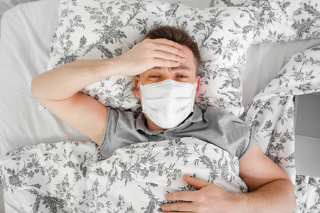 蒙面男子躺在家里的床上生病.呆在家里照片