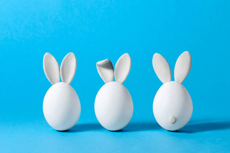 蓝色背景上有兔子耳朵的复活节彩蛋。创意贺卡。极简主义概念。复制空间