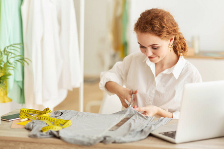 支架缝纫女裁缝用剪刀剪布,缝制新服装照片