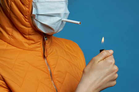 一根烟戴医用防护口罩的小女孩亮了起来,嘴里叼着一根烟,穿过口罩照片