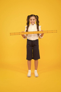 告诉我距离。孩子校服拿着尺子。小学生可爱的女孩拿着大尺子。几何学校科目。教育与学校理念。尺寸和测量。学生学习几何