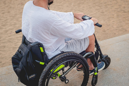 坐在轮椅上的残疾人在沙滩上骑着电动滑板车