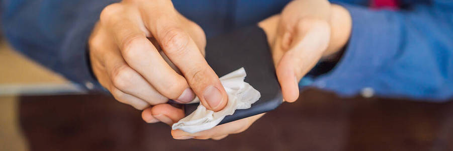 男人用酒精或消毒剂清洁智能手机屏幕.