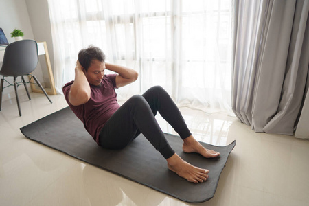 亚洲男人在家里做仰卧起坐锻炼图片
