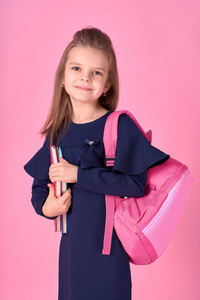 返校概念半翻照片可爱自信美丽聪明的女孩穿着校服连衣裙粉色明亮背包孤立的笔记本