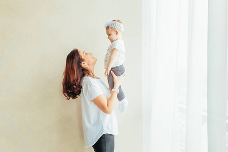 妇女和婴儿小女孩在室内温迪欧附近的白色卧室里放松.家庭幸福.