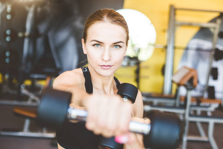 用哑铃举重训练健身房。健身运动的妇女正在举哑铃。健身肌肉身体。锻炼在健身房。