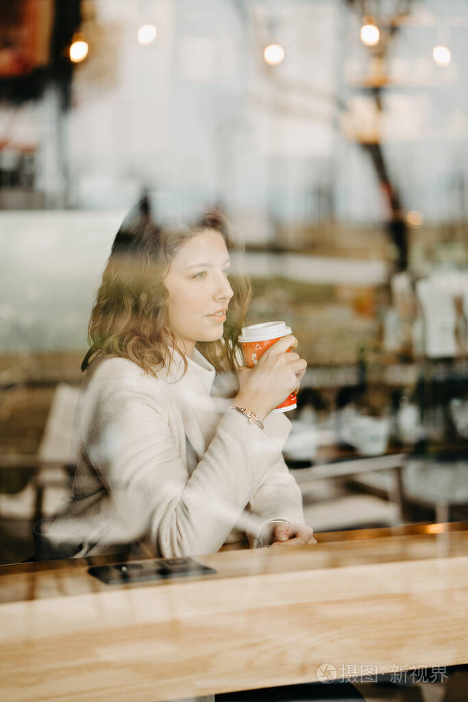 美丽的年轻女孩坐在餐厅里喝咖啡