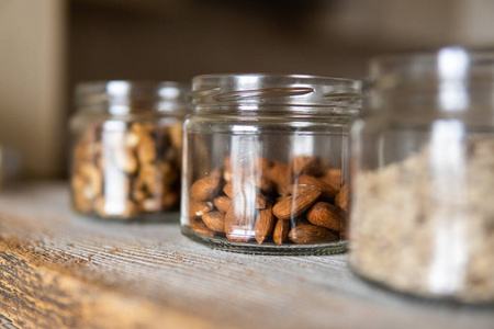葵花籽，核桃和杏仁放在一个罐子里，放在白色的复古桌子上，背景是厨房。坚果是一种健康的素食蛋白质和营养食品。古旧木头上的坚果。