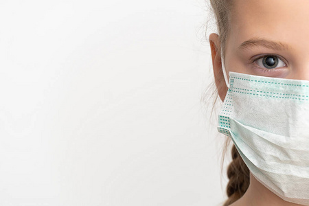 女孩在医用口罩因空气，半边脸，肖像，特写，白色背景，复印空间。外科口罩可抵御冠状病毒和其他病毒