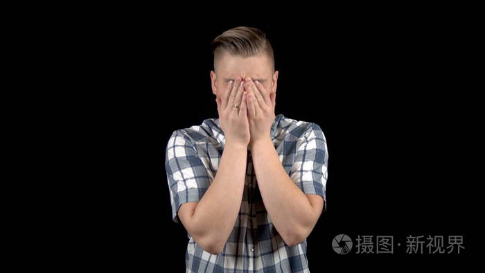 那个年轻人在哭情绪化的男人在黑色背景下哭泣