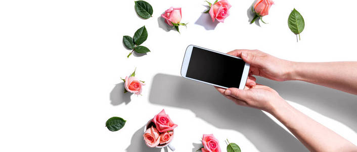 一个拿着粉色玫瑰的智能手机的女人