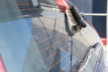 用刷子和洗发水手洗汽车后窗。自助快速洗车