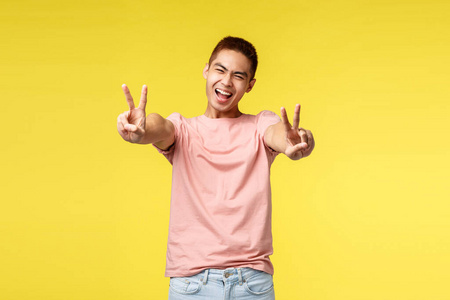 开朗,热情,帅气的亚洲帅哥微笑着眯着眼睛,露出和平的迹象,享受着暑假