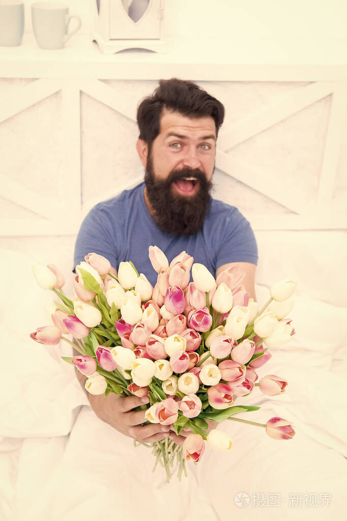 男人在床上休息时拿着郁金香花束.送花服务.生日纪念日.