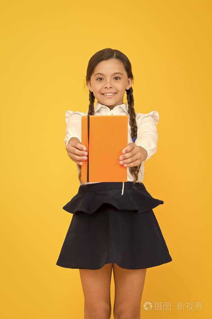 照片 爱读书为乐.可爱的小学生拿着黄色背景的读物.