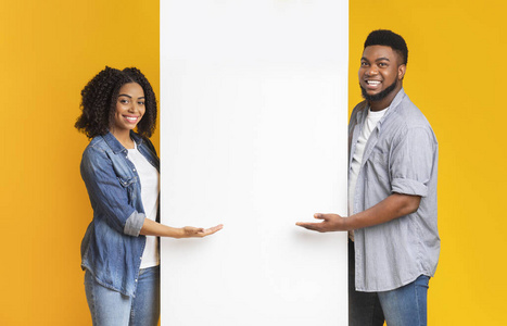 积极的非洲夫妇张开手掌指着白色广告牌