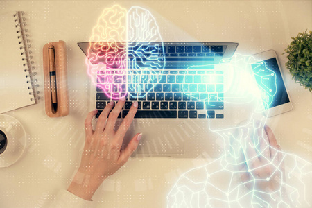 女性手在电脑上工作和男性在ar眼镜全息图绘制的双重曝光。俯视图。虚拟现实概念。