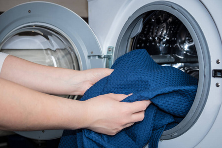 把衣服放在洗衣机里的女人的手照片