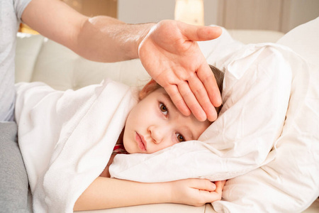 爸爸用手抚摸病人女儿的额头.照片