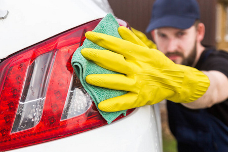 清洁服务。穿制服戴黄色手套的男子在洗车机里洗车身
