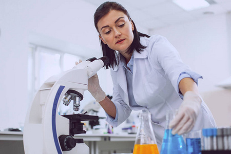 严肃的女生物学家在显微镜下工作