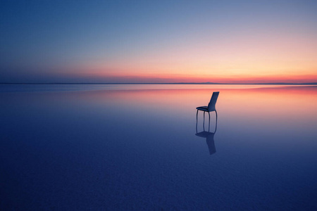 落日时在平静的湖水中的椅子图片
