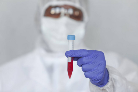 身穿化学防护服的医生拿着血样，对冠状病毒COVID19进行检测，以阻止病毒的大流行和流行