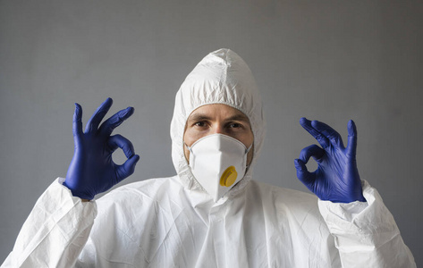 医生穿着白色防护服，戴着医用面罩和橡胶手套，显示一切都很好。在冠状病毒大流行威胁下帮助人们。流行，冠状病毒covid19大流行。